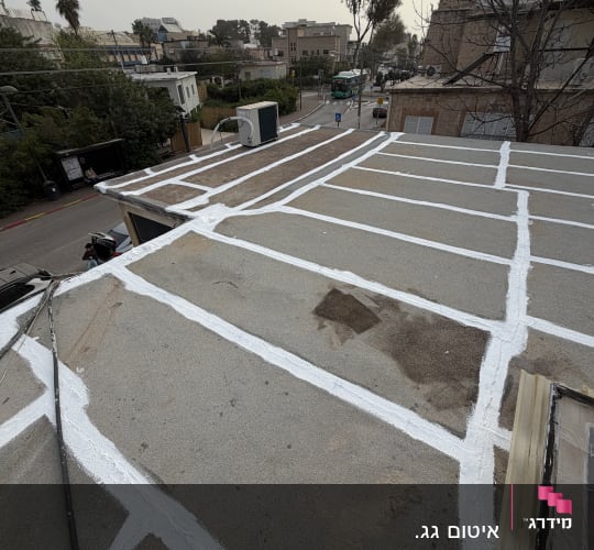 גג עם איטום לבן על רקע עירוני